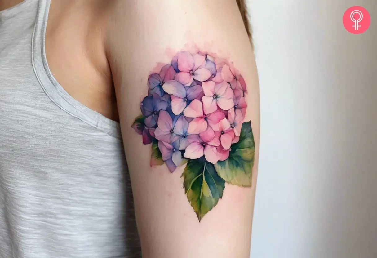 A watercolor hydrangea tattoo on the upper arm of a woman