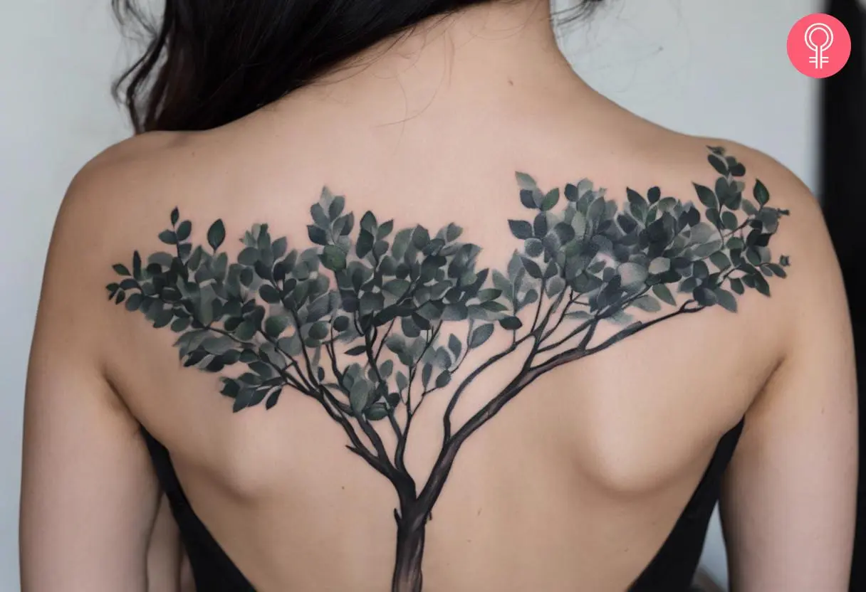 A woman wearing a black eucalyptus tattoo on the back