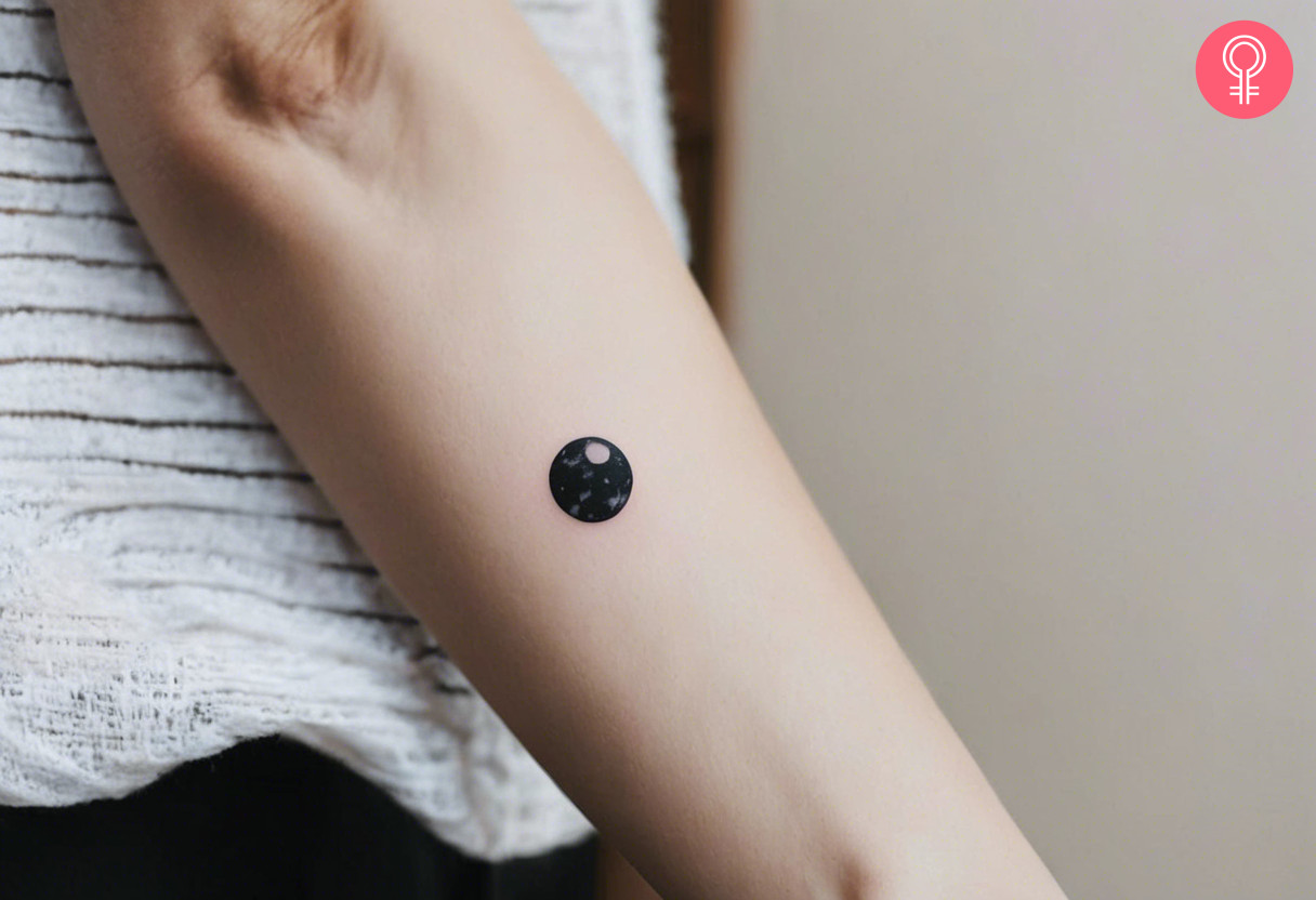 A woman wearing a black marble tattoo on the forearm