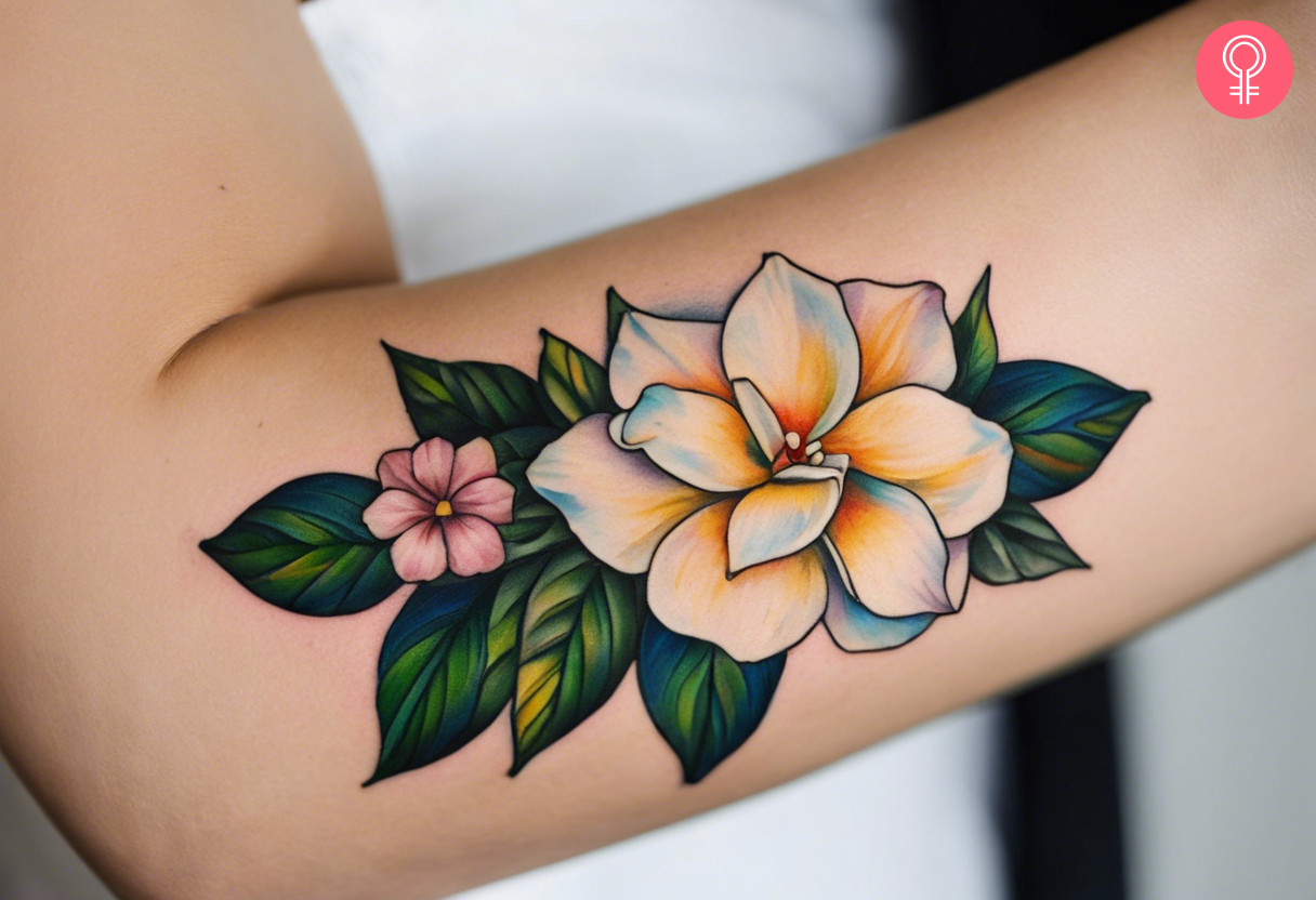 A woman wearing a colorful gardenia tattoo on her lower arm