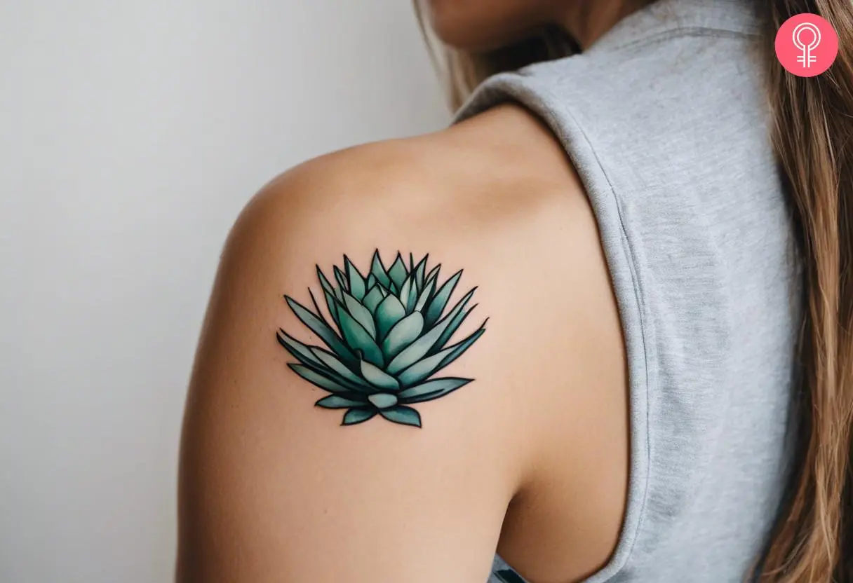 A woman wearing a feminine agave tattoo on the back of the shoulder.