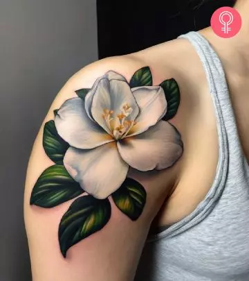 A woman with a vibrant frangipani flower tattoo on her upper arm