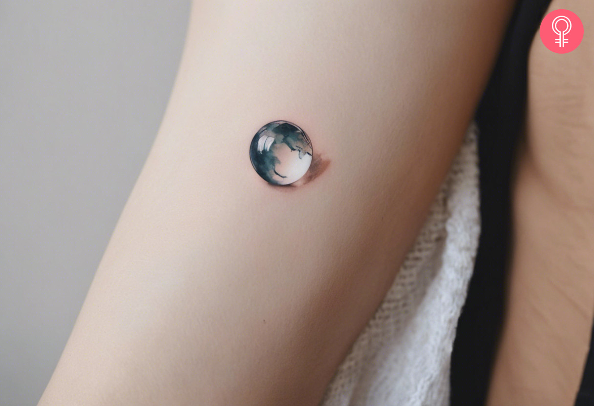 A woman wearing a glass marble tattoo on the lower arm