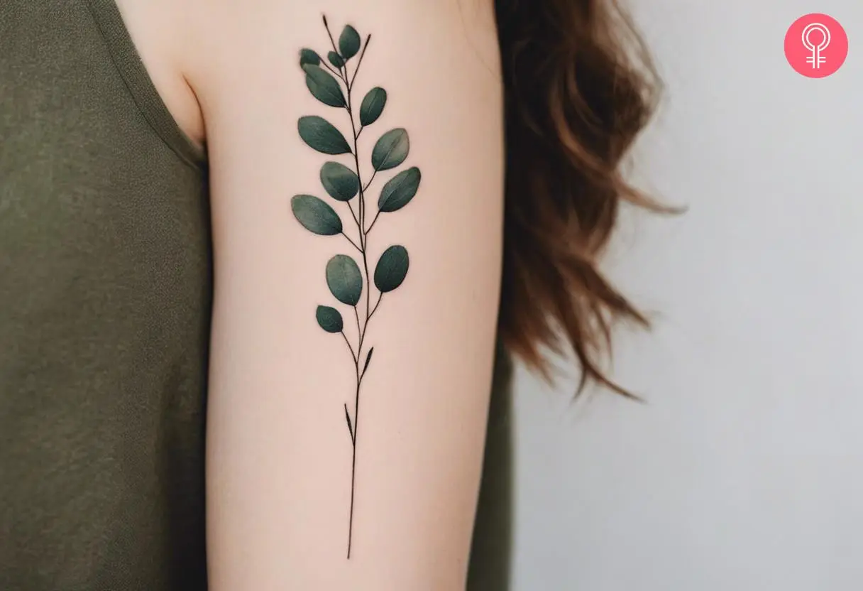 A woman wearing black eucalyptus tattoo on the back of the hand.