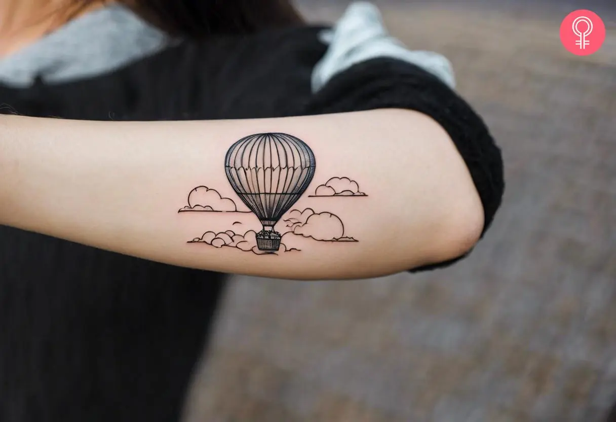 A woman with a fine-line hot air balloon tattoo on her arm