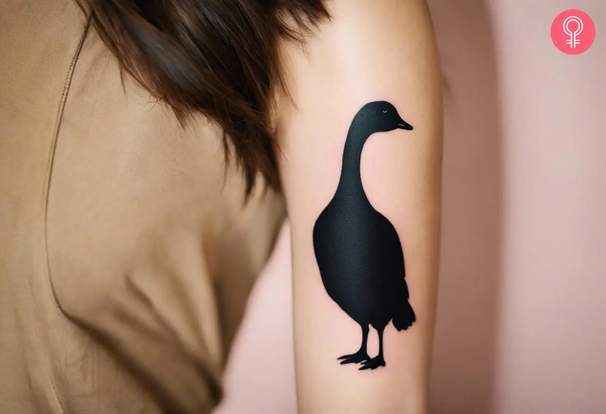 A woman with a goose silhouette tattoo on her upper arm