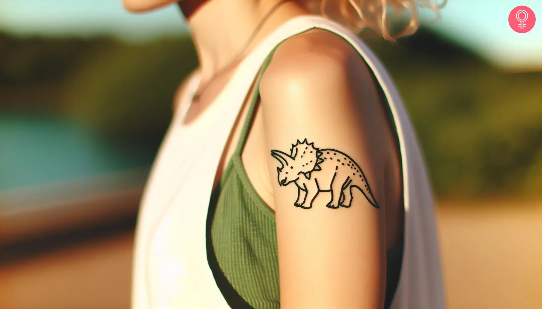 A woman with a minimalistic triceratops tattoo on her upper arm