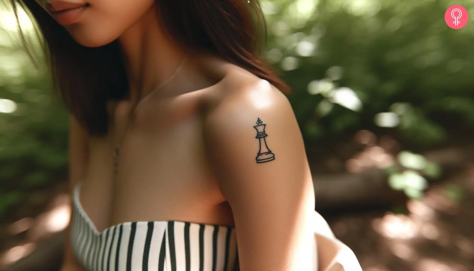 A woman with a small queen chess piece tattoo on her upper arm