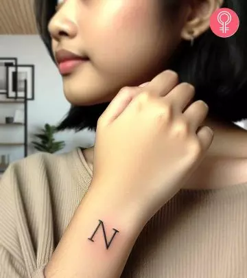 A woman wearing a ‘T’ style letter tattoo on the upper arm.