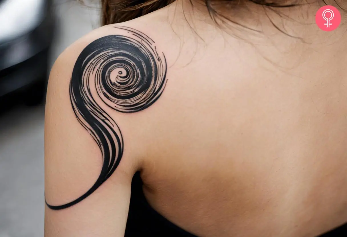 An abstract swirl tattoo on the back shoulder of a woman