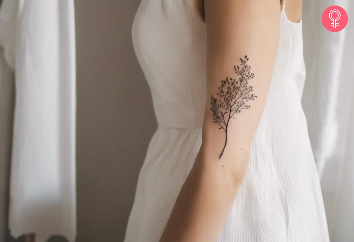 An ash tree branch tattoo on the upper arm of a woman