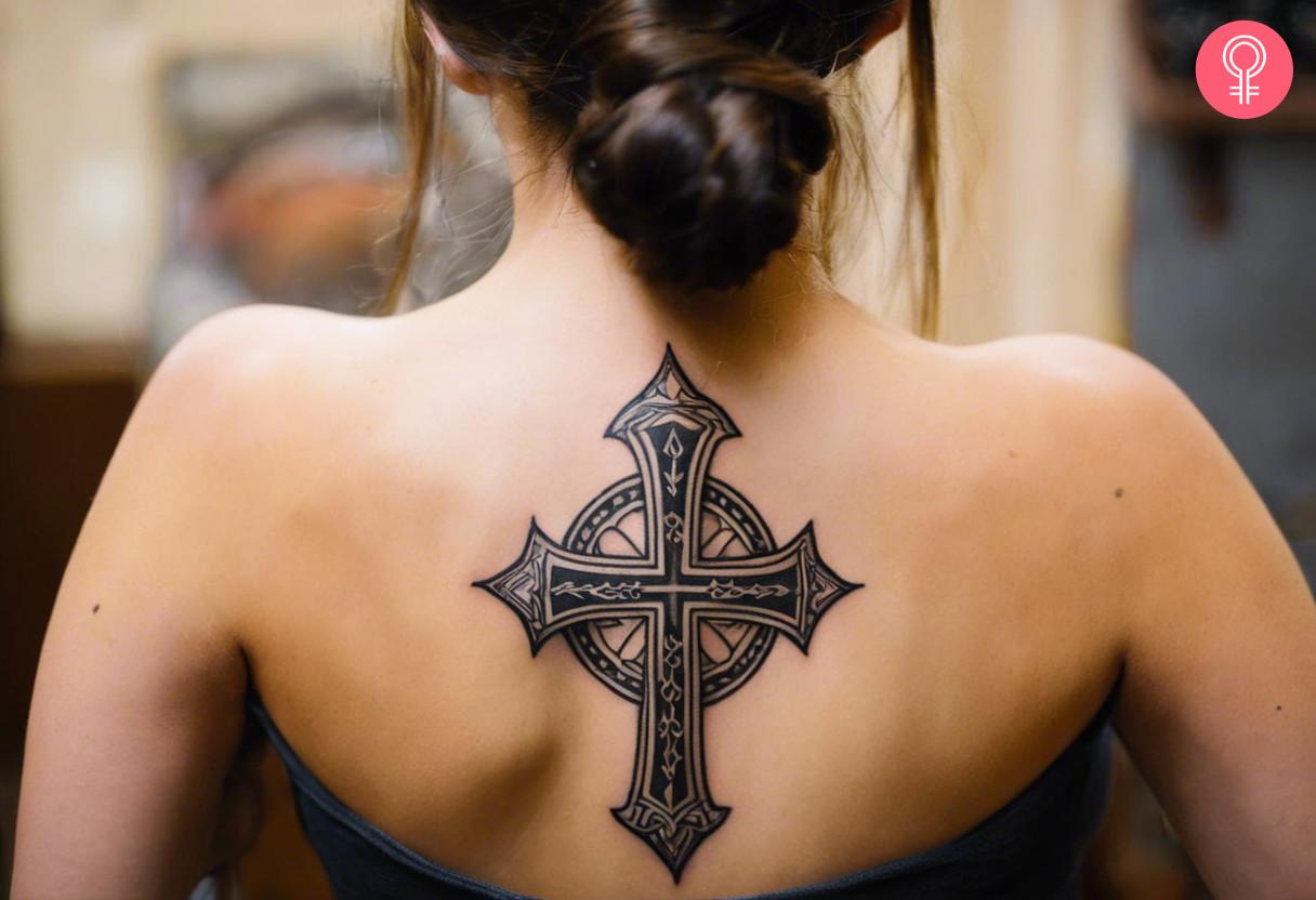 An intricate and beautiful cross tattoo on the back