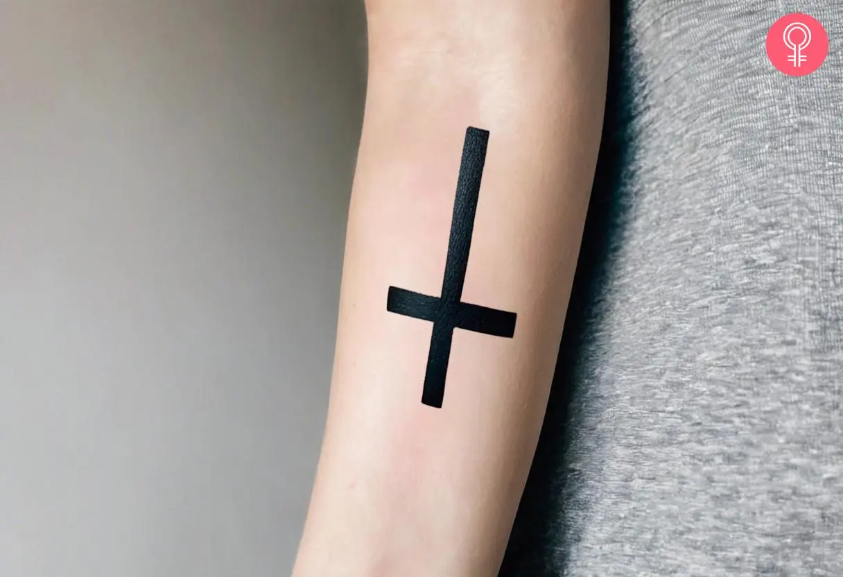 An inverted cross tattoo on a woman’s forearm