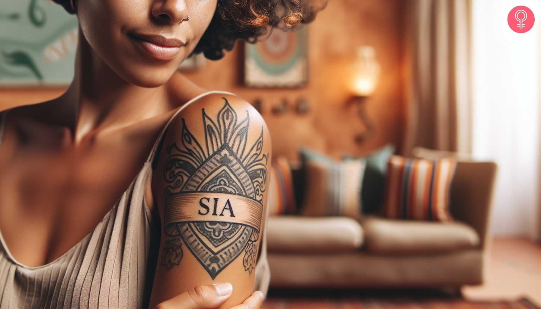 Banner tattoo with the name 'SIA' on the shoulder