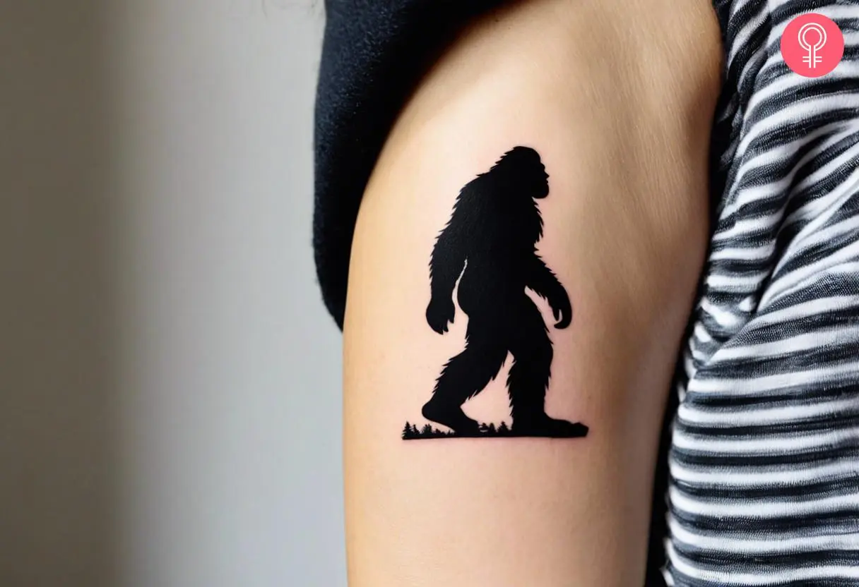 Bigfoot silhouette tattoo on the upper arm of a woman