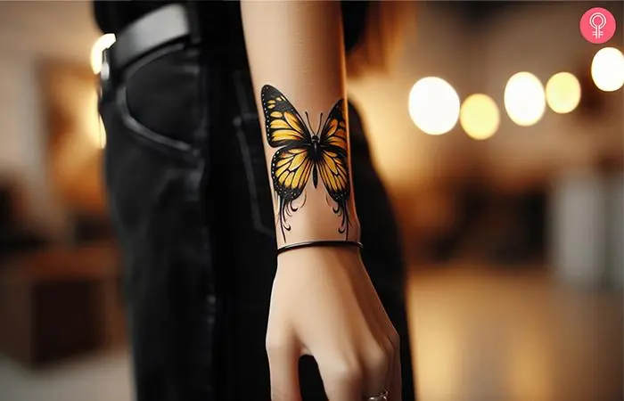 Black and yellow butterfly tattoo on the forearm of a woman