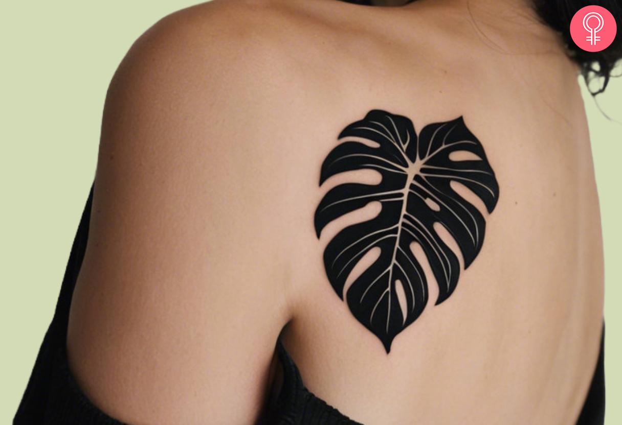 Black Monstera tattoo on a woman’s shoulder