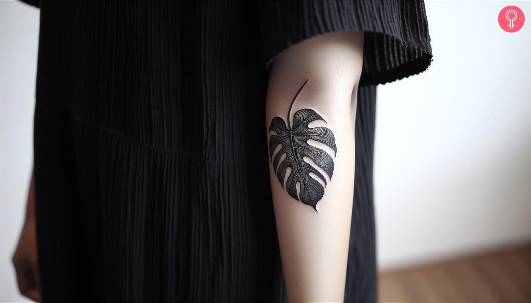 Black-and-white Monstera tattoo on a woman’s arm