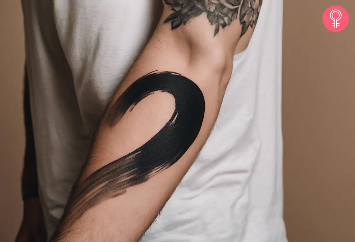 Black brush stroke tattoo on the forearm