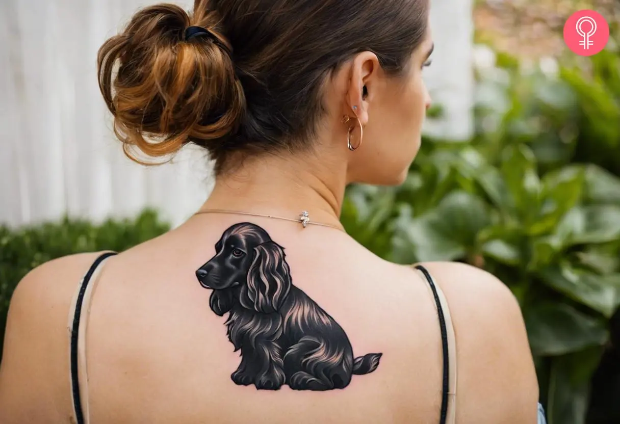 Black cocker spaniel tattoo on a woman’s upper back