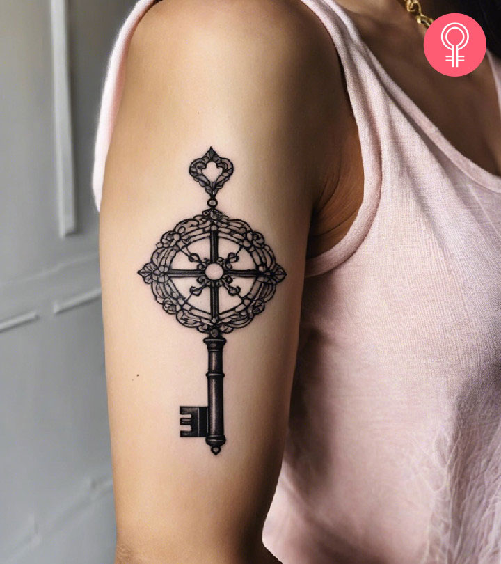 Black line skeleton key tattoo on the upper arm of a woman