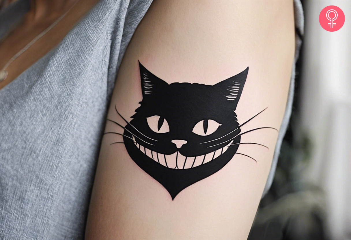 Black simple cheshire cat tattoo on the upper arm