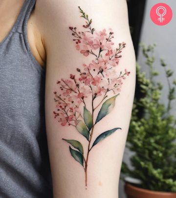 A woman wearing a ‘family birth flower bouquet’ tattoo on the upper arm.