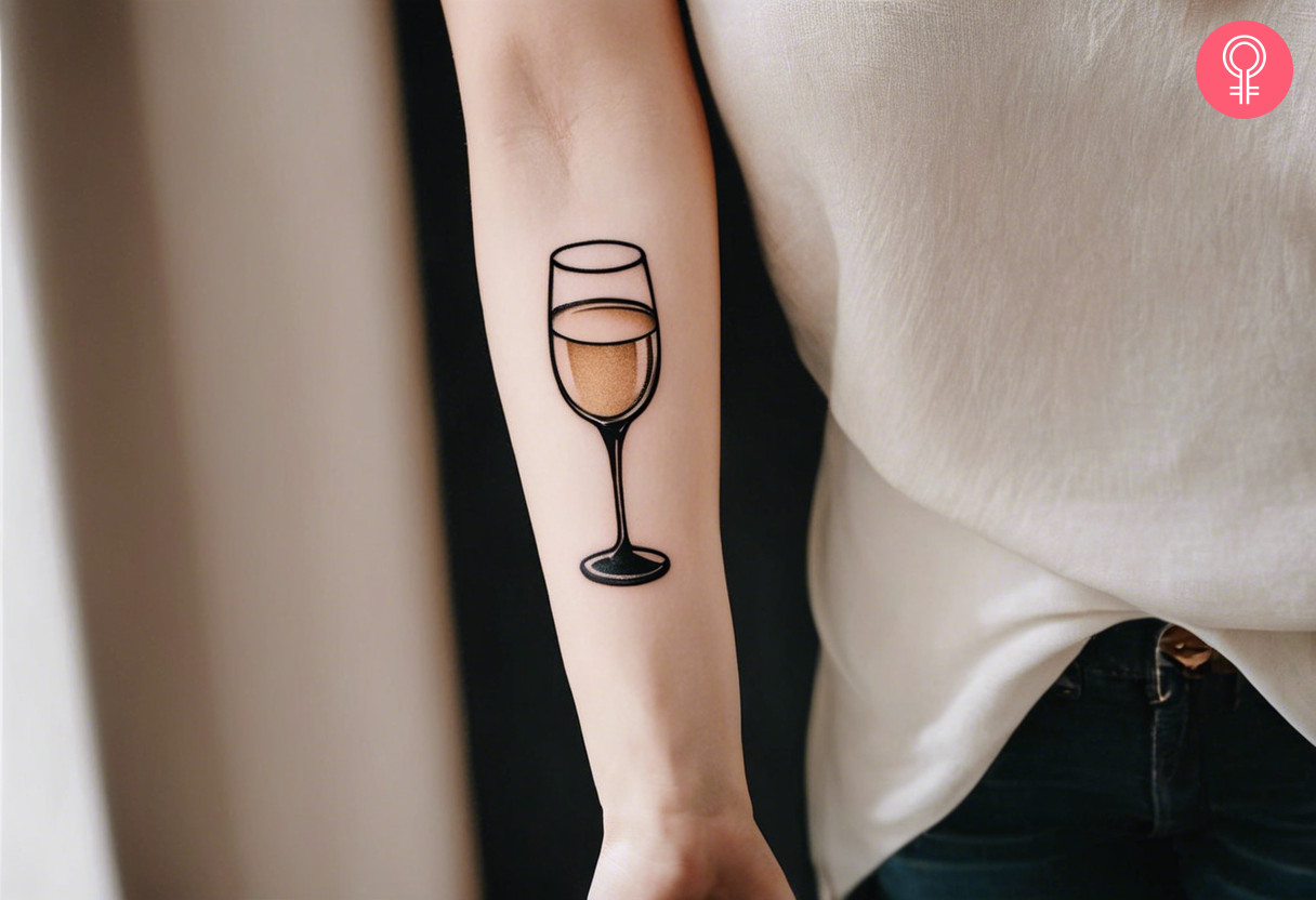 A champagne glass tattoo on the forearm of a woman