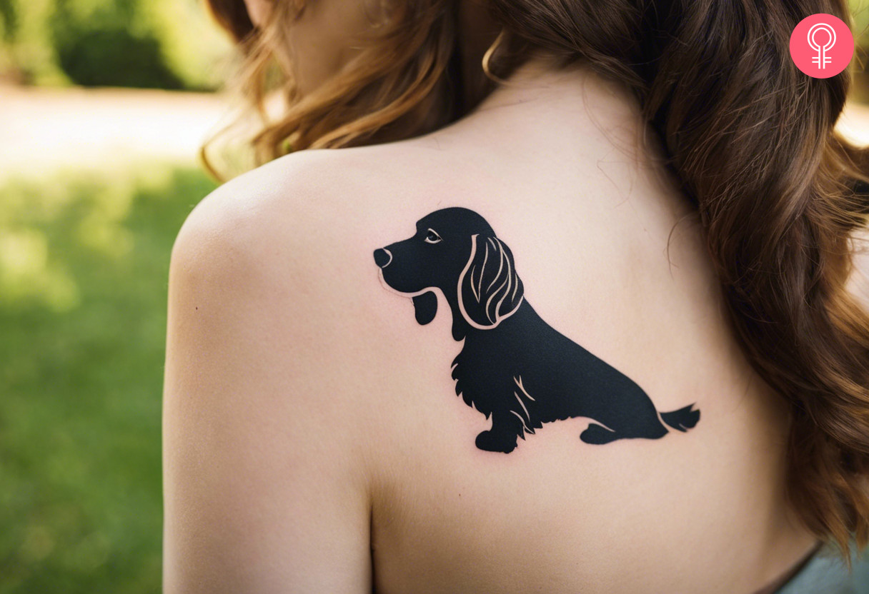 Cocker spaniel silhouette tattoo on a woman’s shoulder