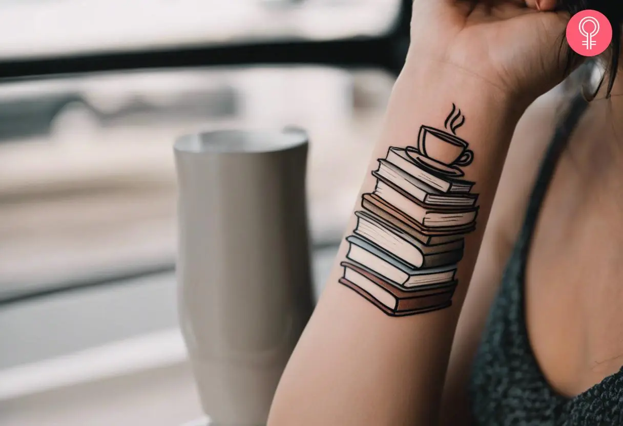 A tattoo showing a coffee and books on a woman’s arm