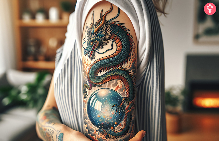 A woman with a dragon and crystal ball tattoo on the upper arm