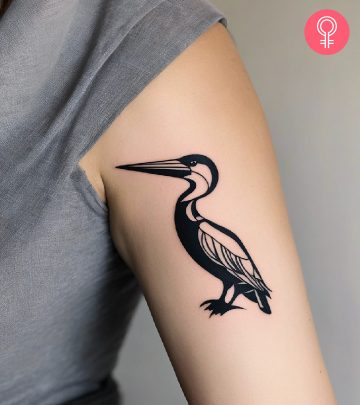 A woman with a black tribal bird tattoo on her upper arm