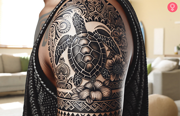 A tattoo on a man’s shoulder featuring a Hawaiian sea turtle and hibiscus