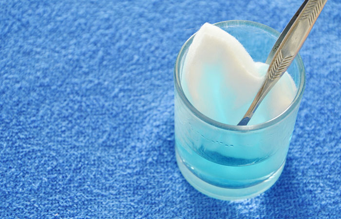 Close-up shot of cotton wool with tweezers picking in blue hydrogen peroxide on glass