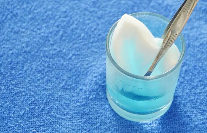 Close-up shot of cotton wool with tweezers picking in blue hydrogen peroxide on glass