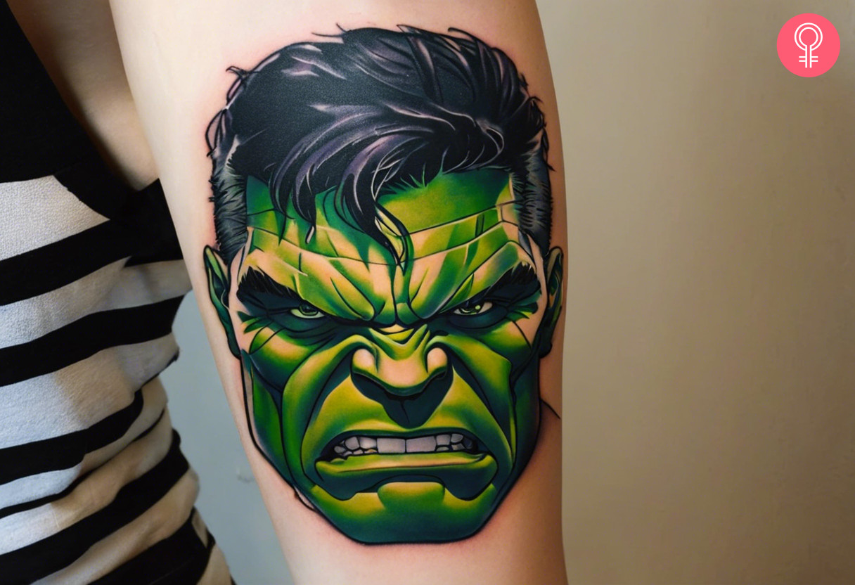 A hulk face tattoo on the upper arm of a woman