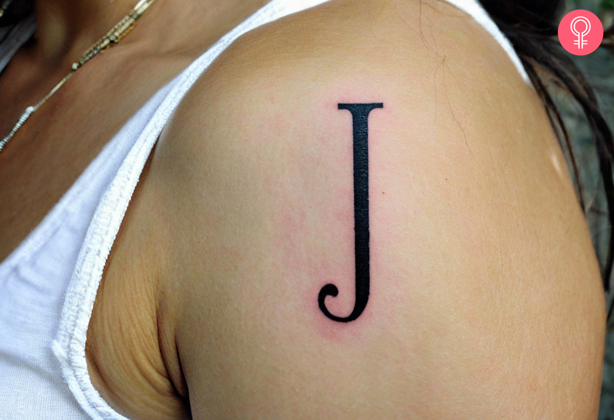 Intricate J letter tattoo on the arm of a woman