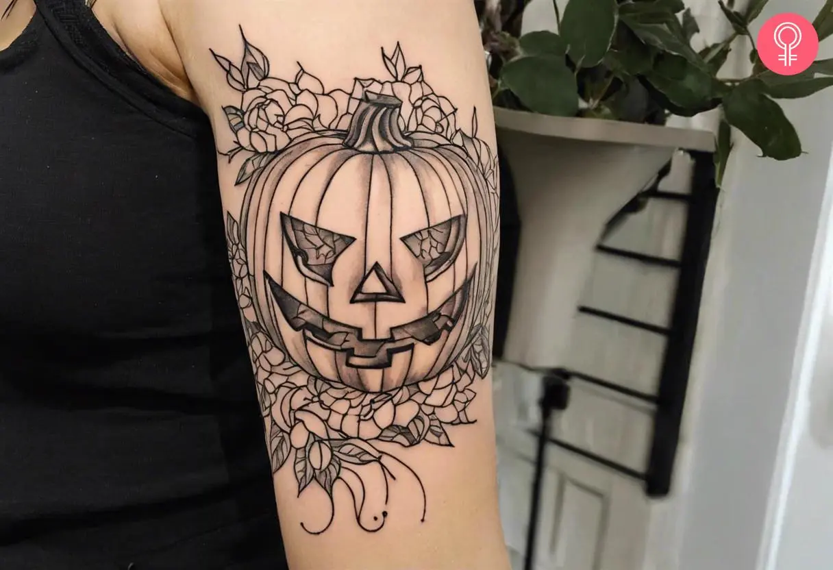 A jack-o'-lantern tattoo outline on the upper arm