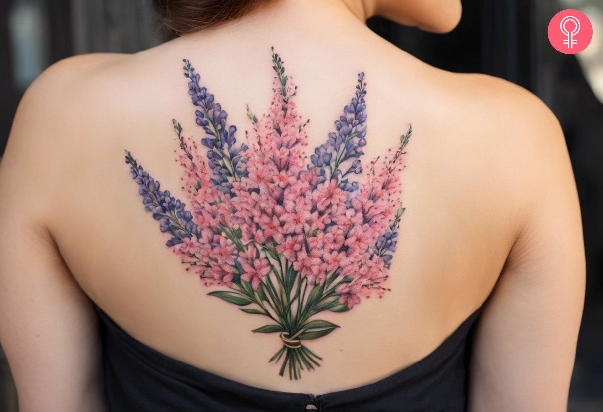 A tattoo on a woman’s back featuring a bunch of baby’s breath and lavender