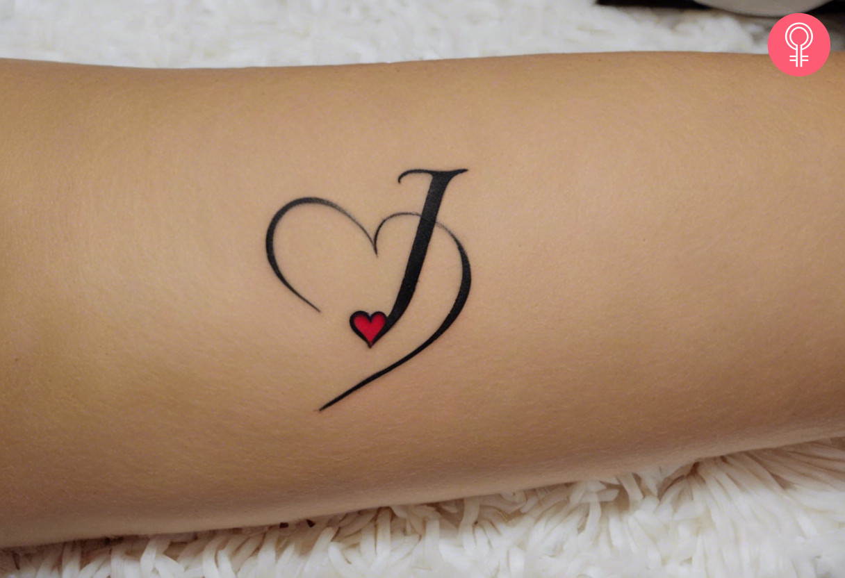 Letter J with heart tattoo on the forearm of a woman