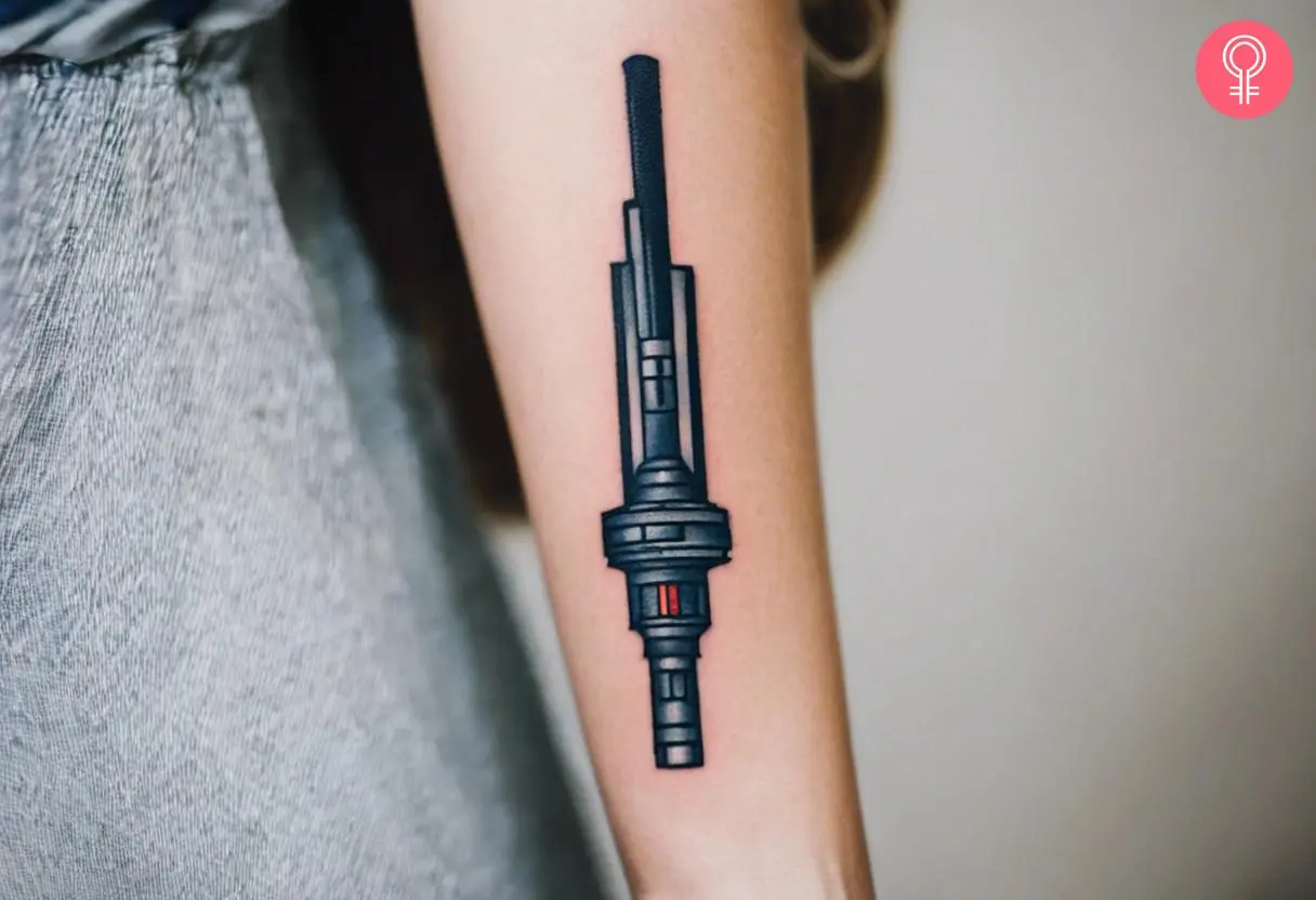 Lightsaber hilt tattoo on a woman’s forearm