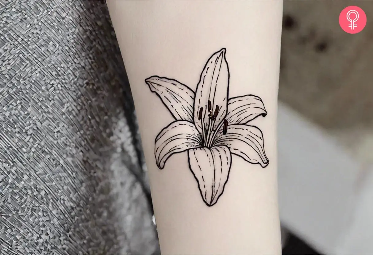 An art nouveau style minimalist lily tattoo on the forearm of a woman