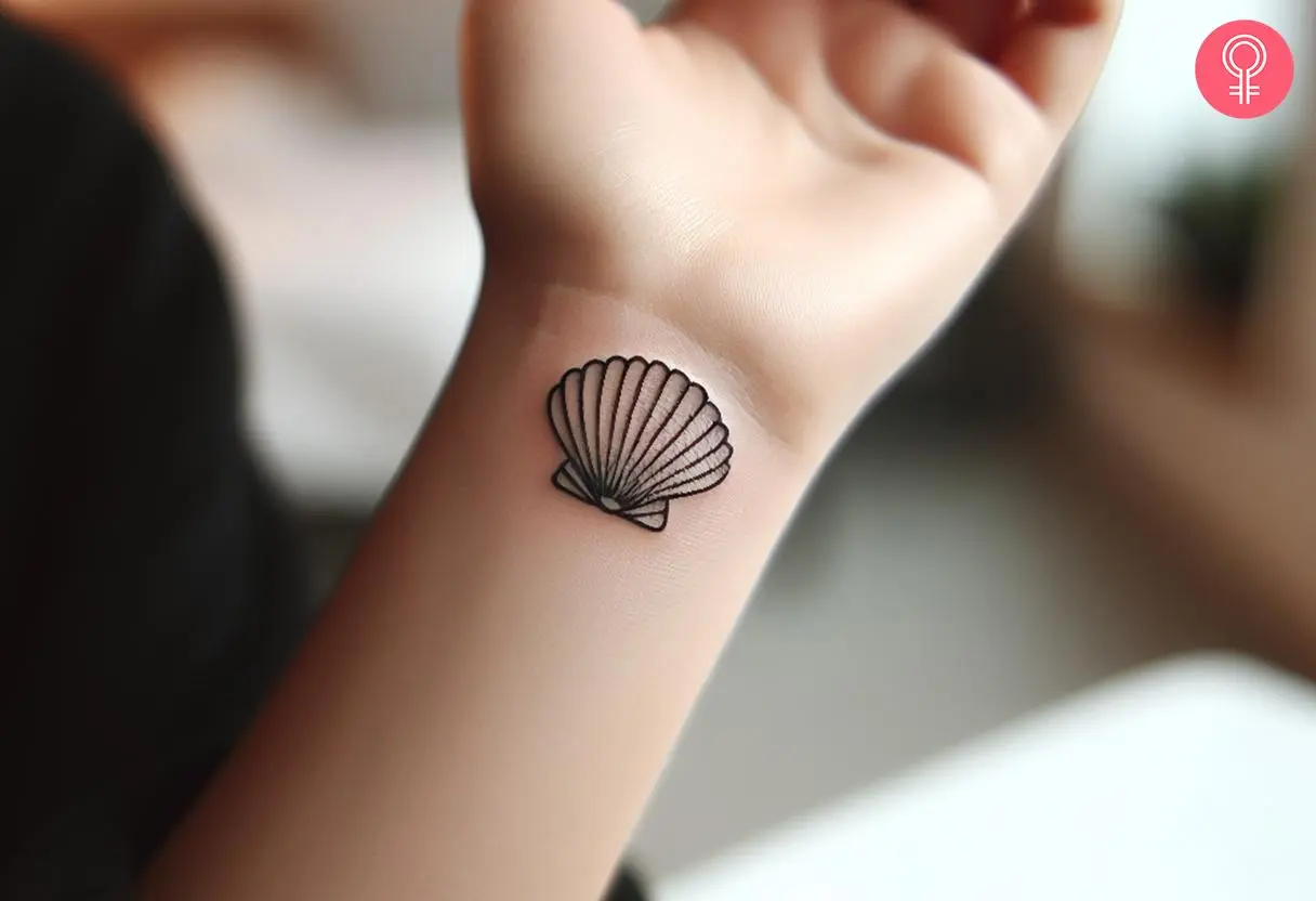 Minimalist clam tattoo on the wrist of a woman