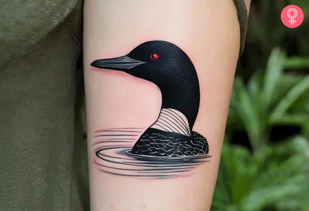 A minimalist loon tattoo on the upper arm