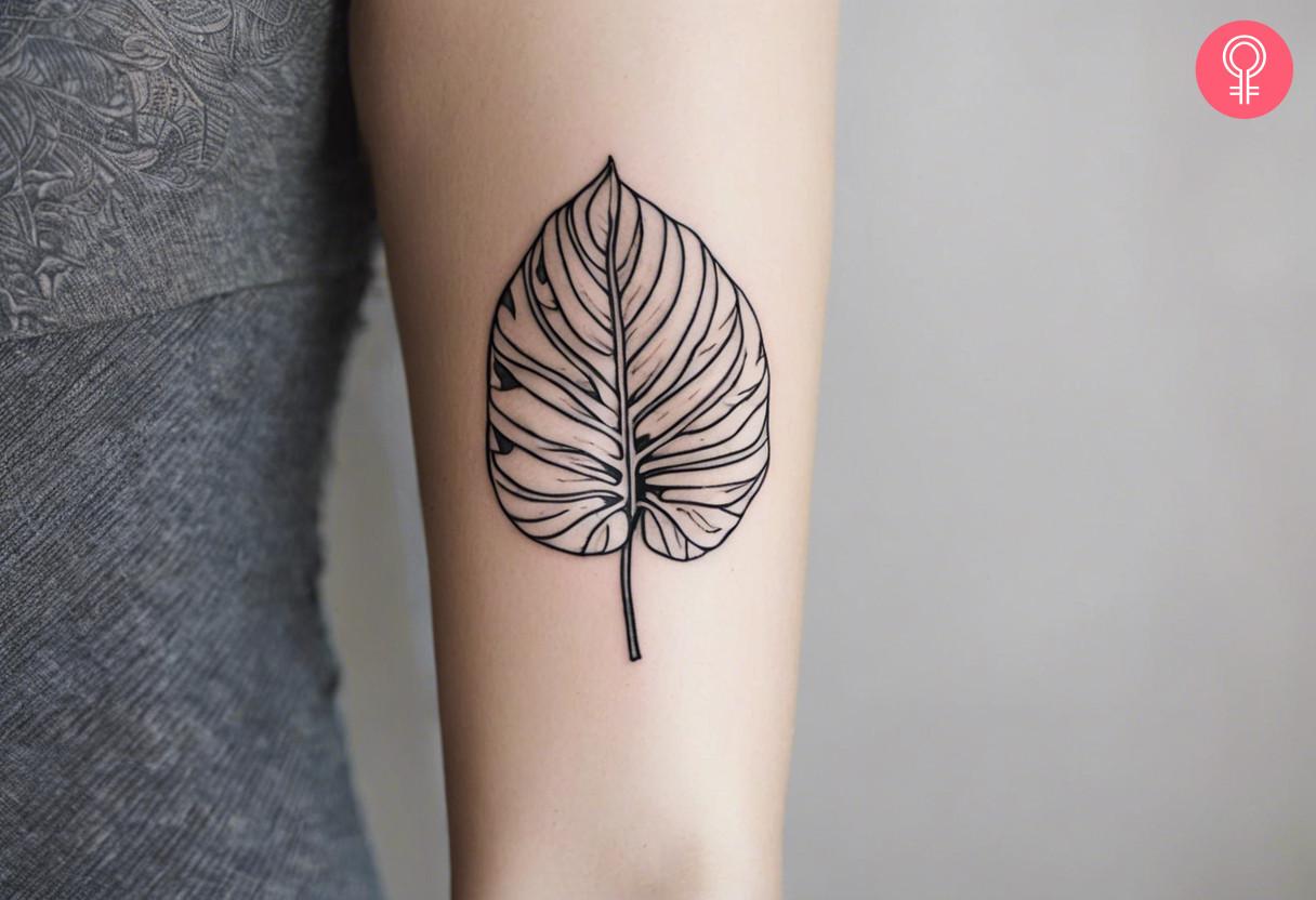 Minimalist Monstera tattoo on a woman’s upper arm