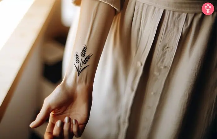 Minimalist wheat tattoo on the wrist of a woman