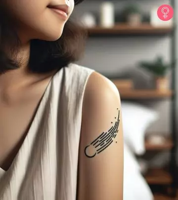 Minimalistic comet tattoo on the upper arm of a woman