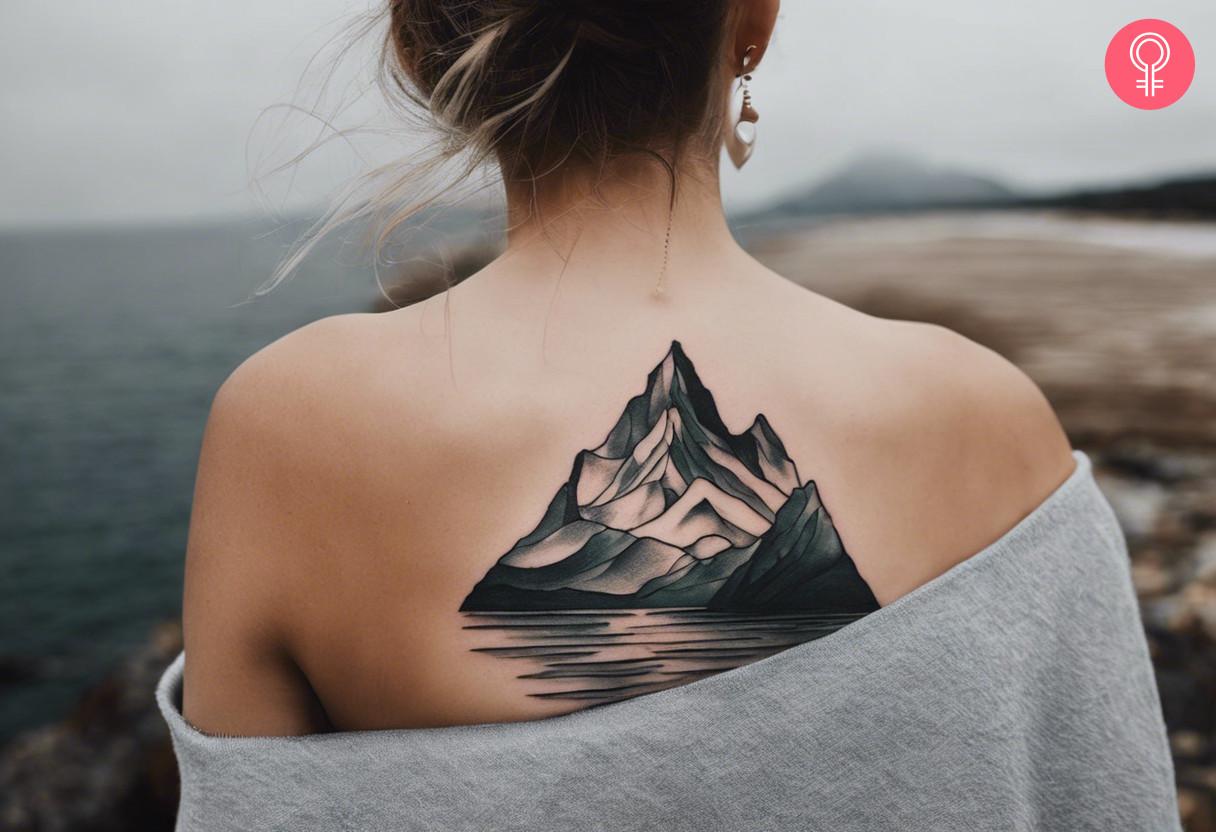 A beautiful black and grey tattoo depicting mountain peaks and the ocean