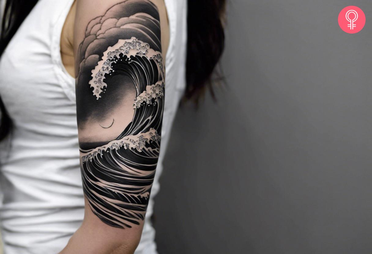 A black and white ocean waves tattoo that covers the upper arm