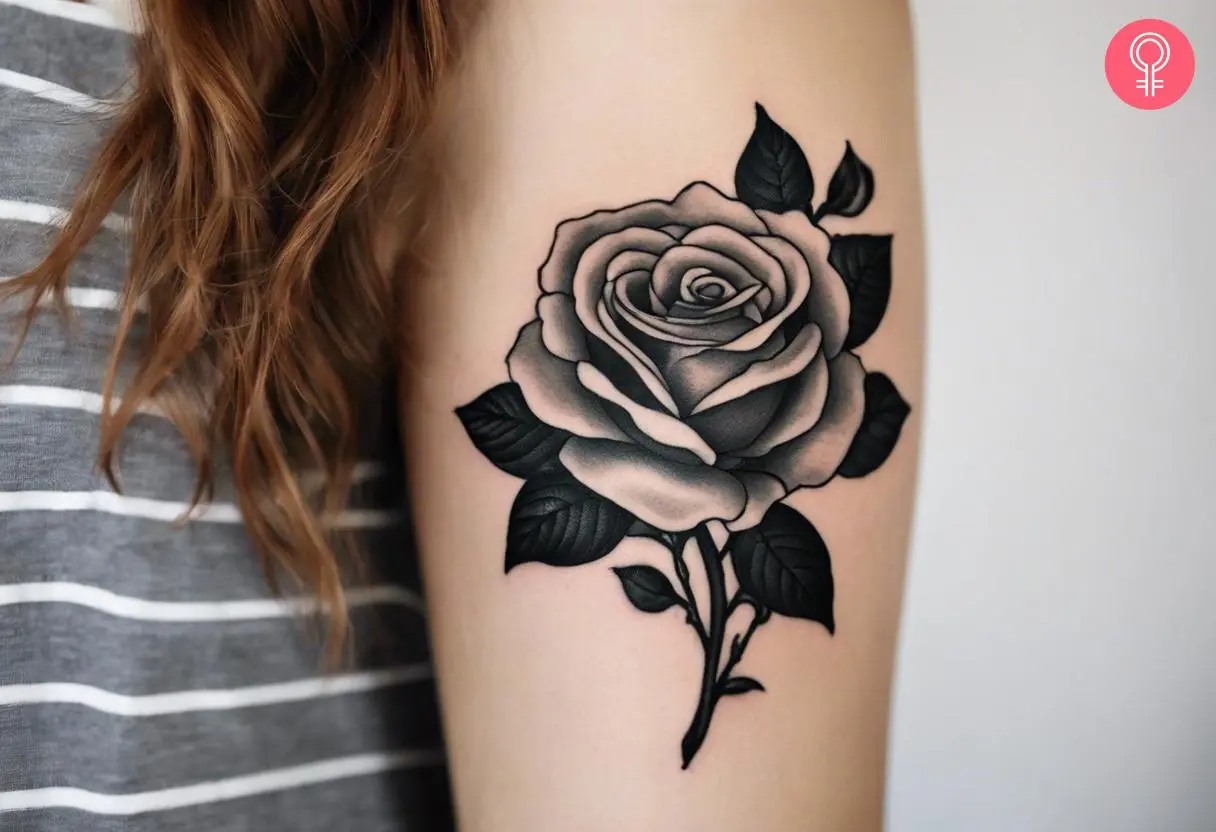 An old school black and gray tattoo on a woman’s upper arm